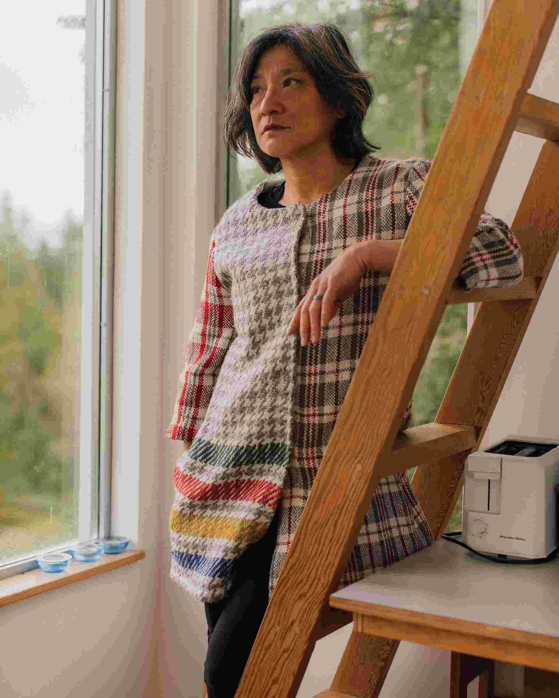 Germaine Koh standing leaning on a ladder