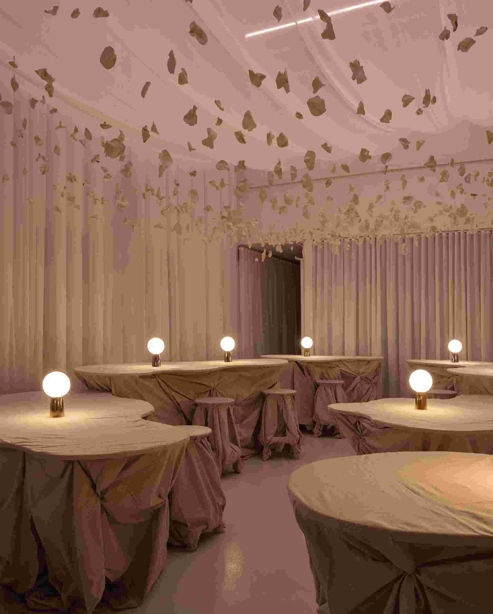 Soft pink room with draping table cloths, wall curtains, and soft objects hanging from the ceiling.