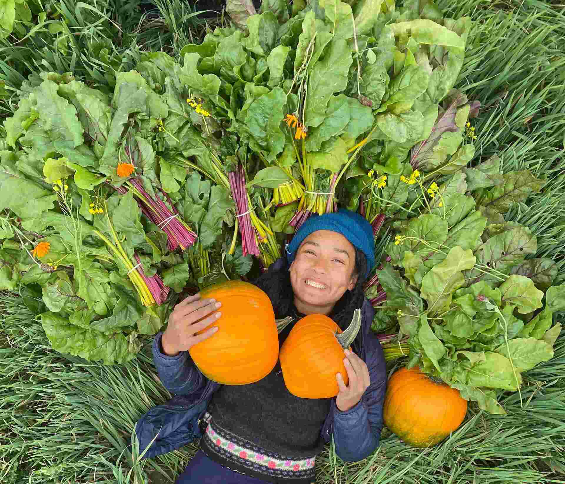 Food Security - 28-Woman-lying-in-greens-holding-pumpkins-and-smiling