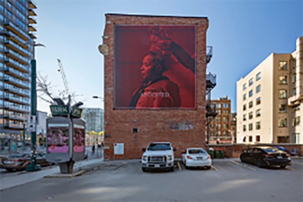 Side of building with large mural of artist. 