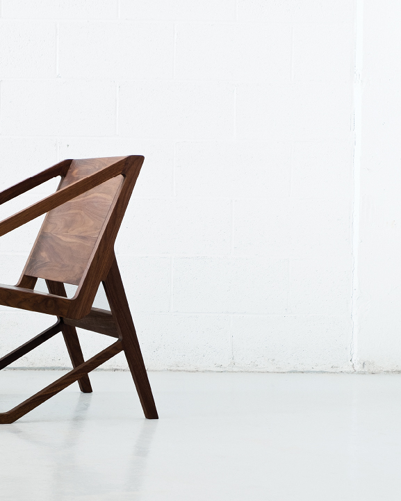 Wooden chair sits on white floor with white backdrop.