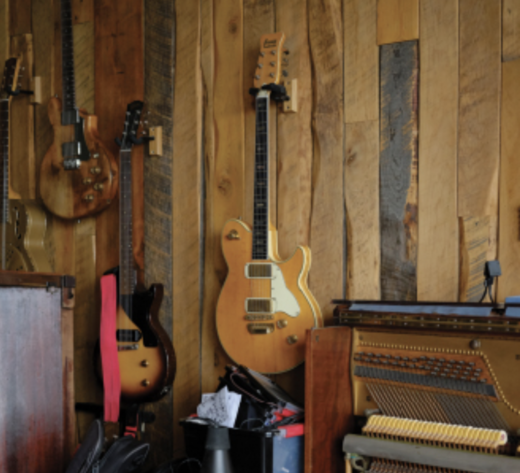 Guitars and other various instruments line wood wall
